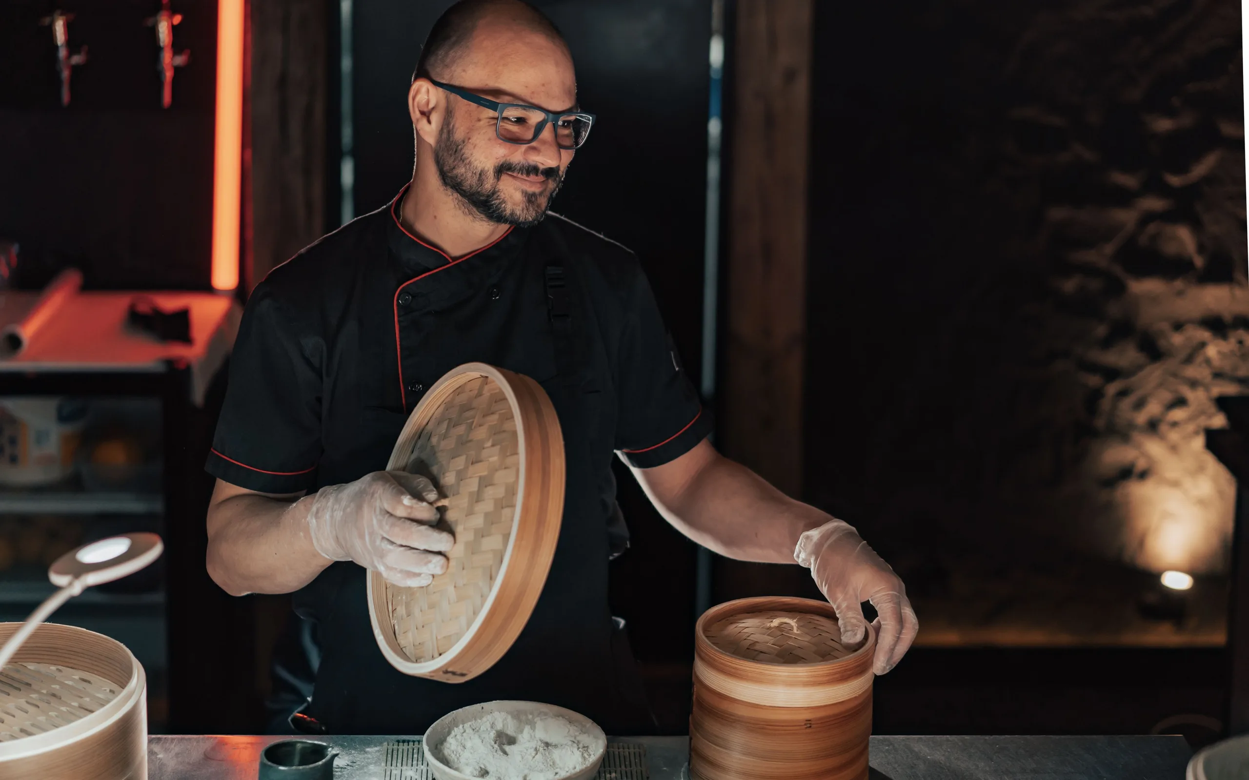 Un cuisinier soulève les étages d’un panier vapeur en bambou au-dessus d’une casserole fumante